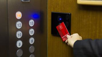 A hand inserting a red card into an elevator card reader.