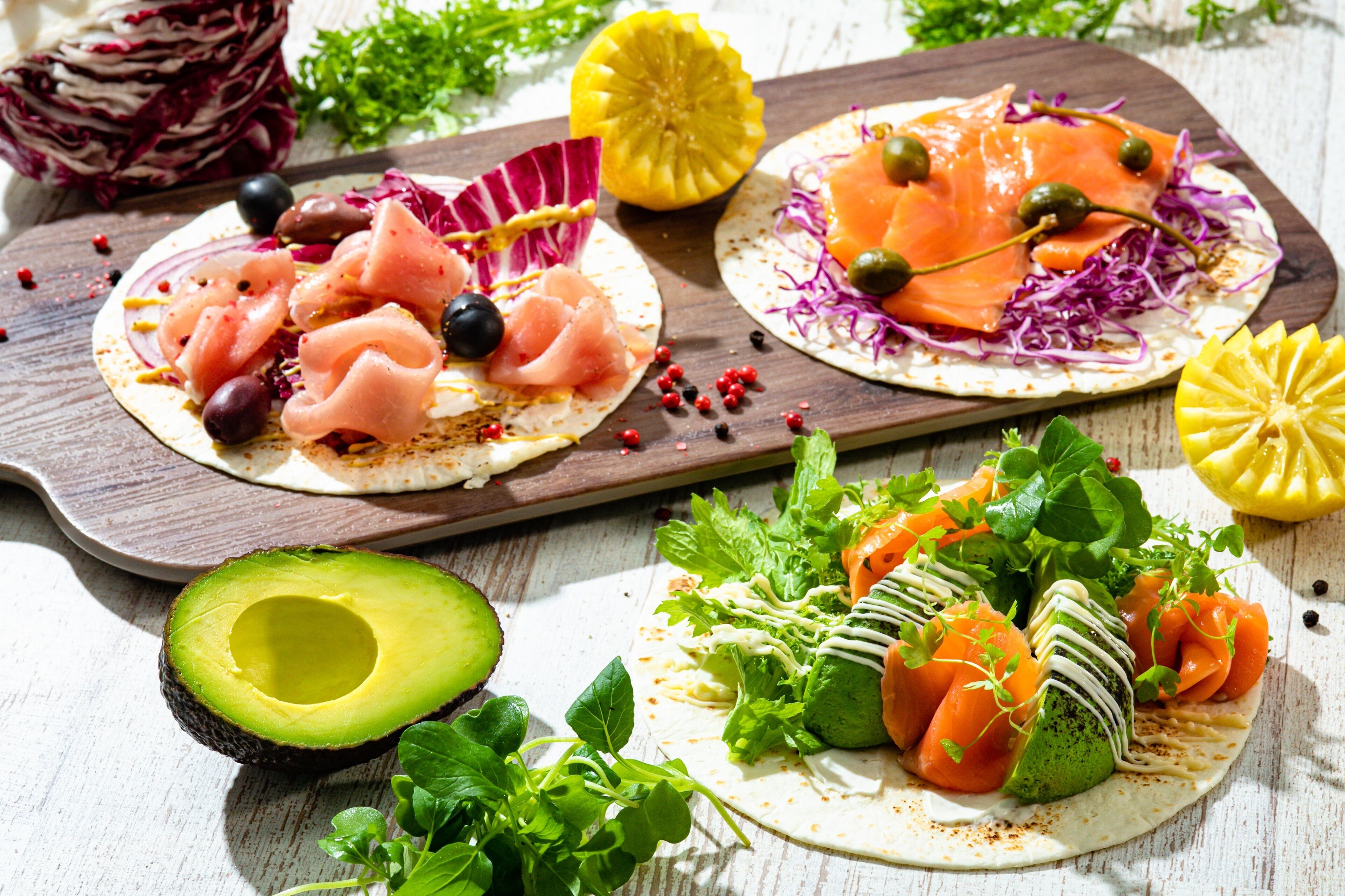 A wooden board with three open-faced sandwiches, each with different toppings.