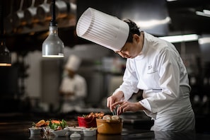 Un chef cuisinier préparant des plats dans une cuisine professionnelle.