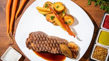 Een bord met steak, geroosterde aardappelen en wortelen.
