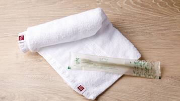 A white towel and a tube of toothpaste on a wooden surface.