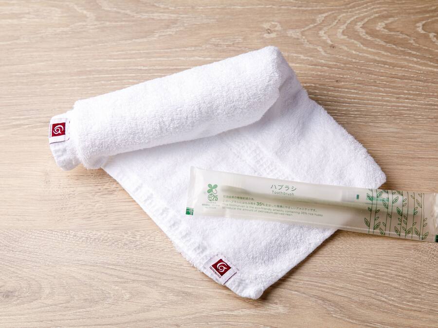 A white towel and a tube of toothpaste on a wooden surface.