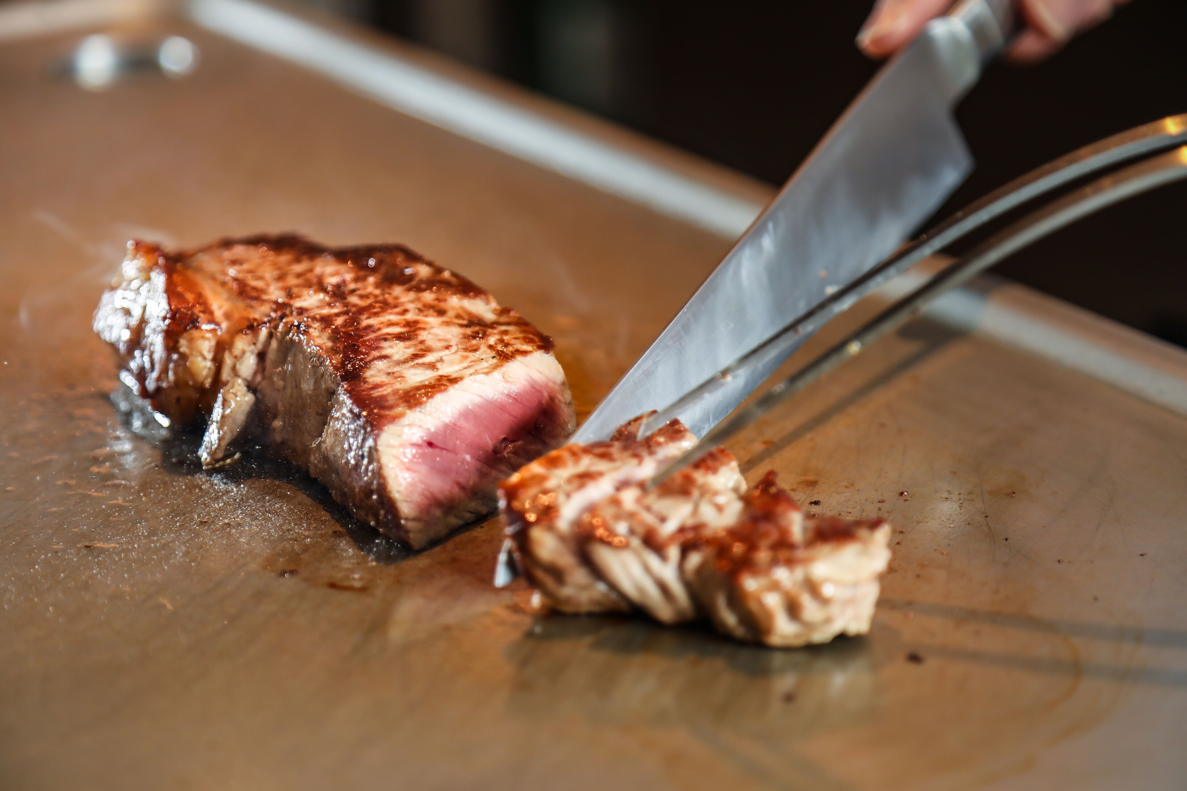 A steak being sliced on a cutting board.