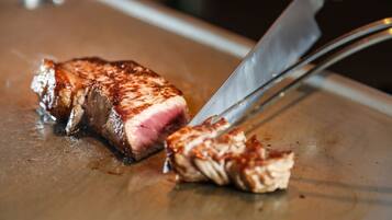 On voit une personne découper un steak sur une planche à découper.