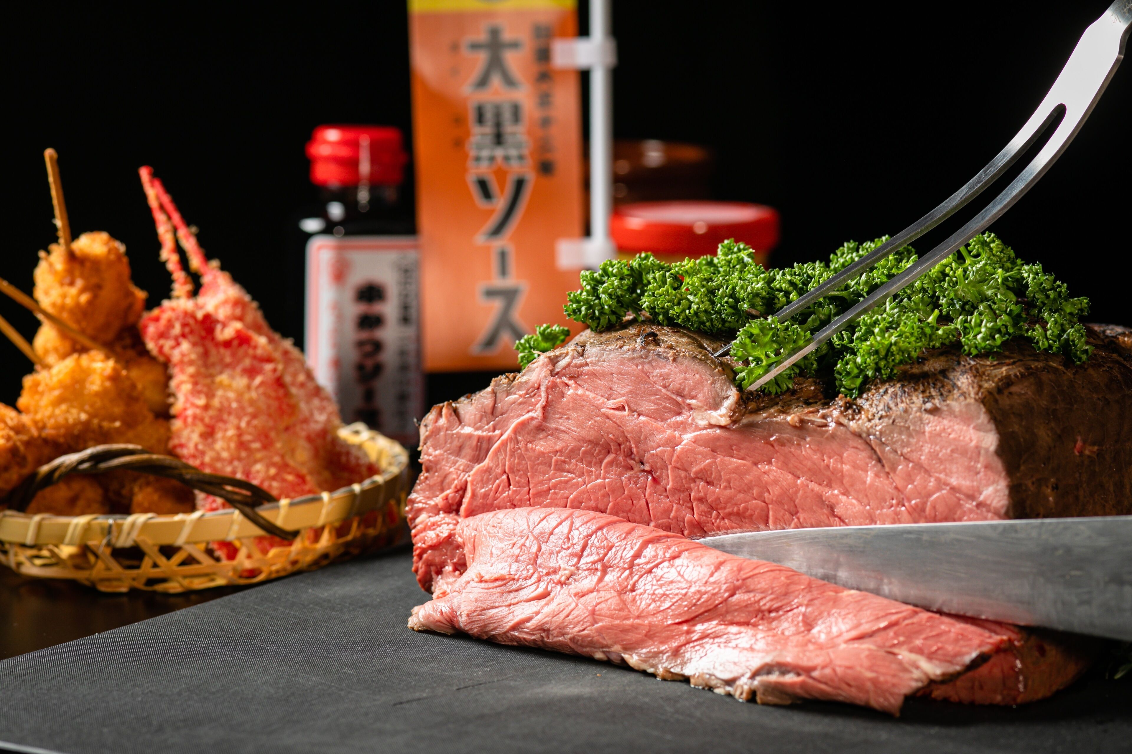 A large piece of meat with a knife on top, garnished with green leaves, and surrounded by food items.