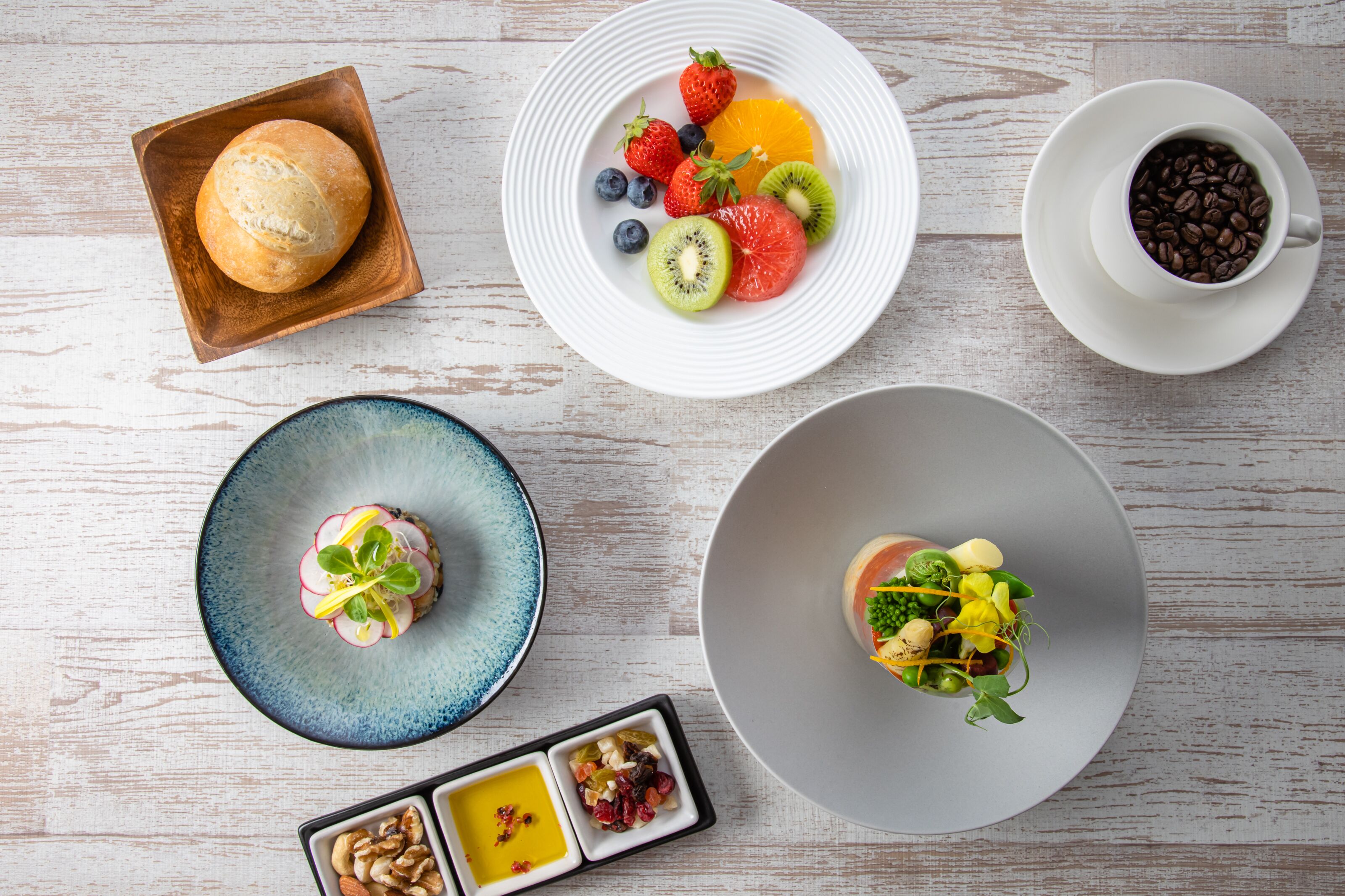 Uma mesa com diversos alimentos, incluindo pão, frutas, café e uma salada.