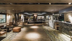 Een ruime lobby met een centraal zitgedeelte, een receptiebalie en uitzicht op het aangrenzende restaurant.