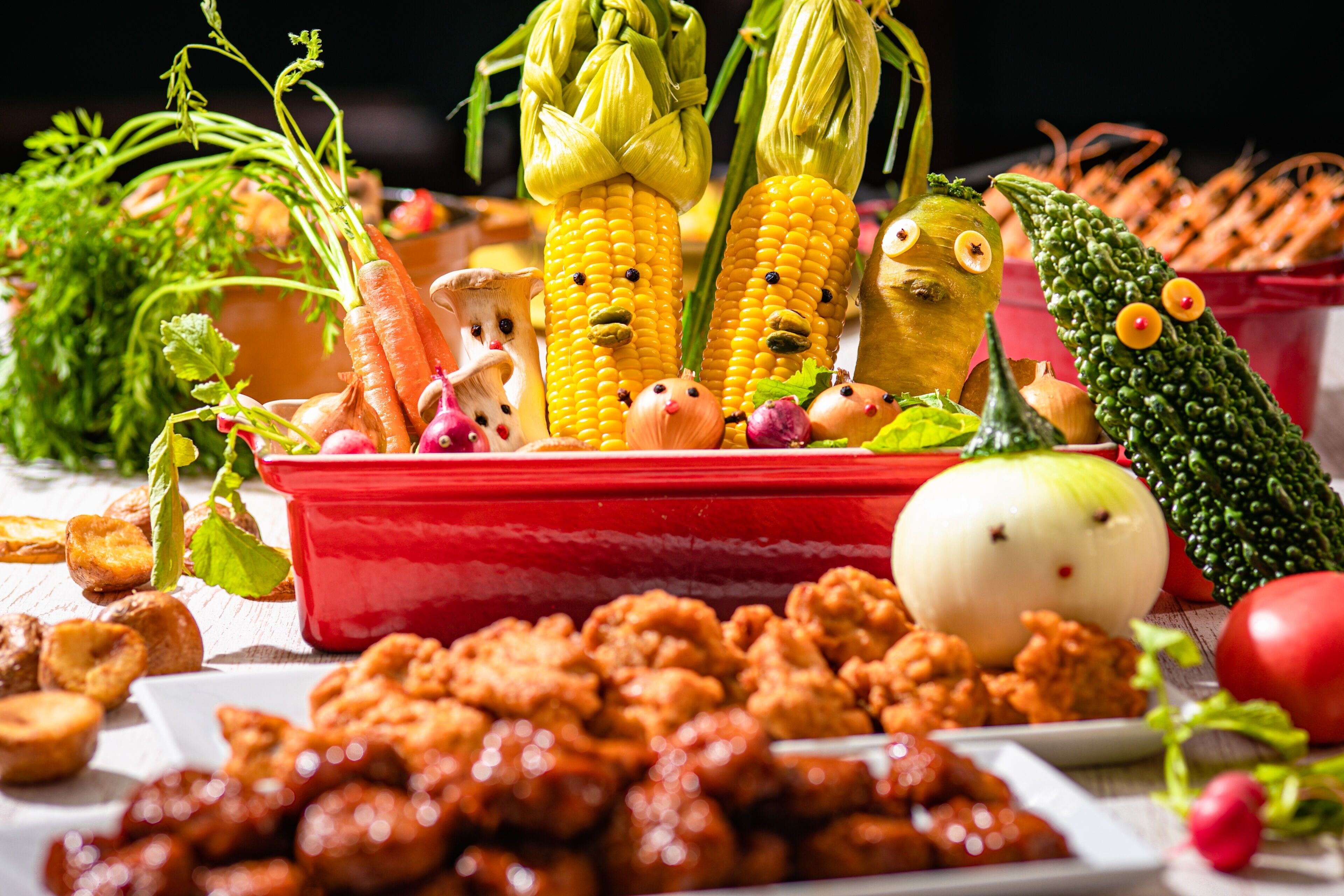 Une variété de légumes et de fruits, notamment du maïs, des carottes et des tomates, disposés sur une table.