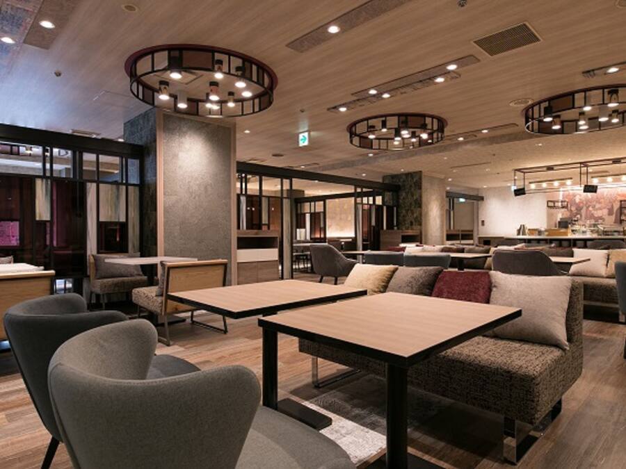 Un interior moderno con luces de techo redondas, mesas de madera y zonas de estar acogedoras.