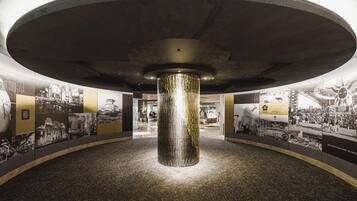 A circular room with a central column, walls with historical photographs, and a ceiling with a circular design.