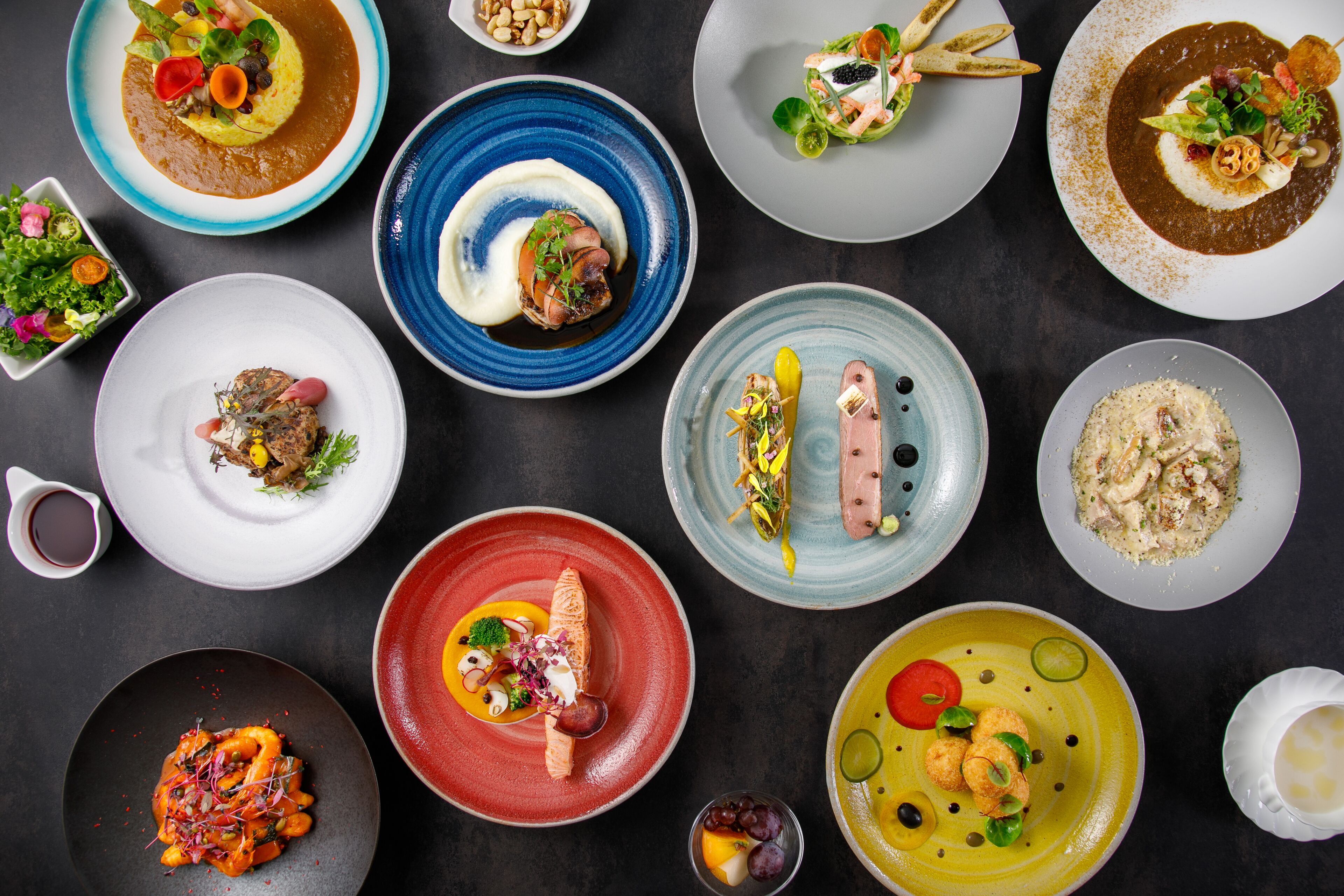 A variety of dishes on different plates, arranged on a dark surface.