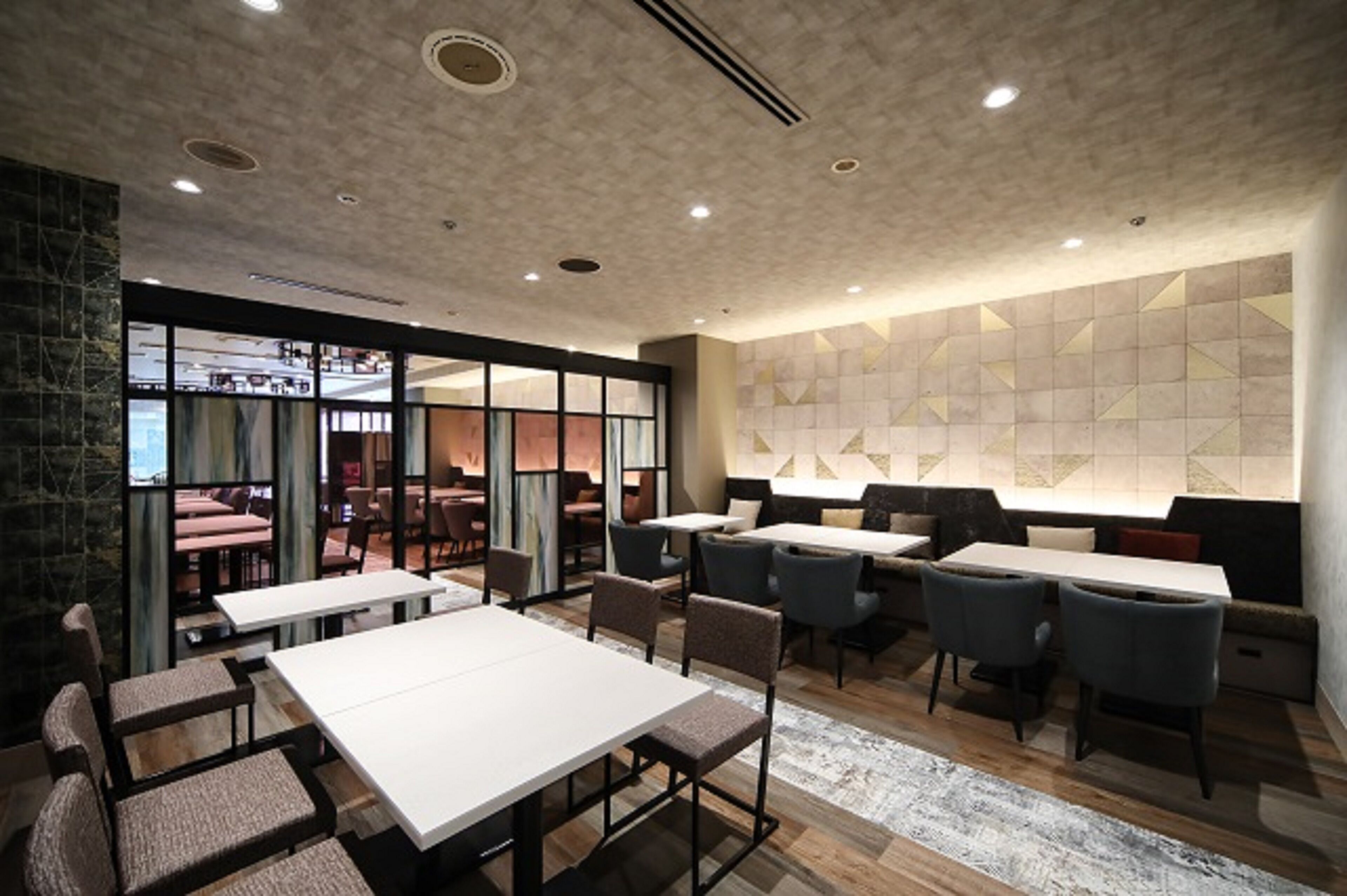 A modern restaurant with a mix of seating options, including tables and booths, and a large window providing a view of the dining area.