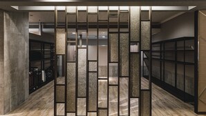 Een modern interieur met houten vloer, een centraal scheidingswand met verticale panelen, en een trap naar een hoger niveau.