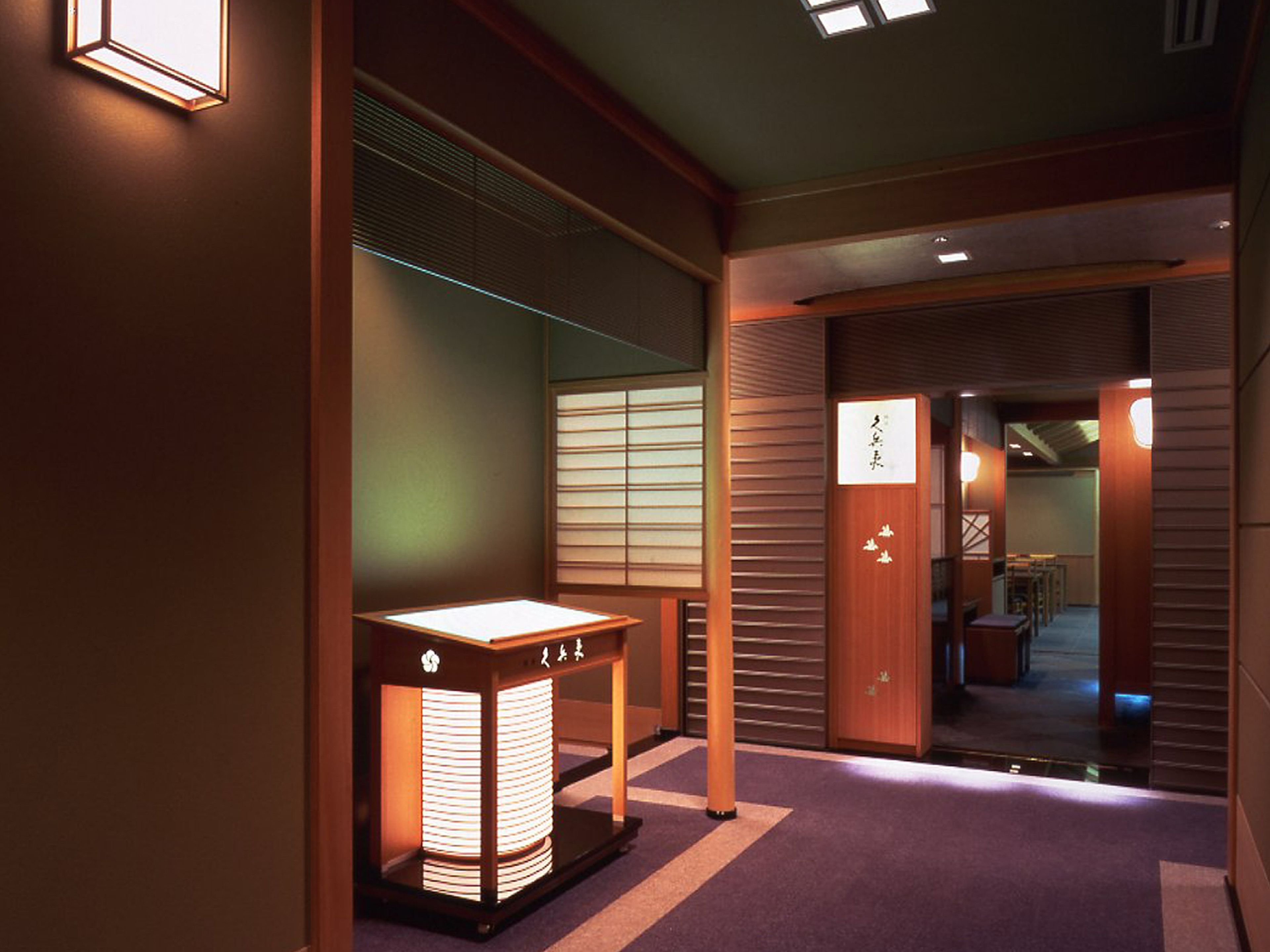 A traditional Japanese interior with tatami flooring, sliding doors, and a reception desk with a lantern.