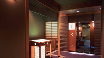 A traditional Japanese interior with tatami flooring, sliding doors, and a reception desk with a lantern.
