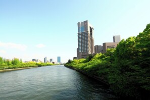 A river with buildings on one side and greenery on the other. - Imperial Hotel, Osaka (Osaka)