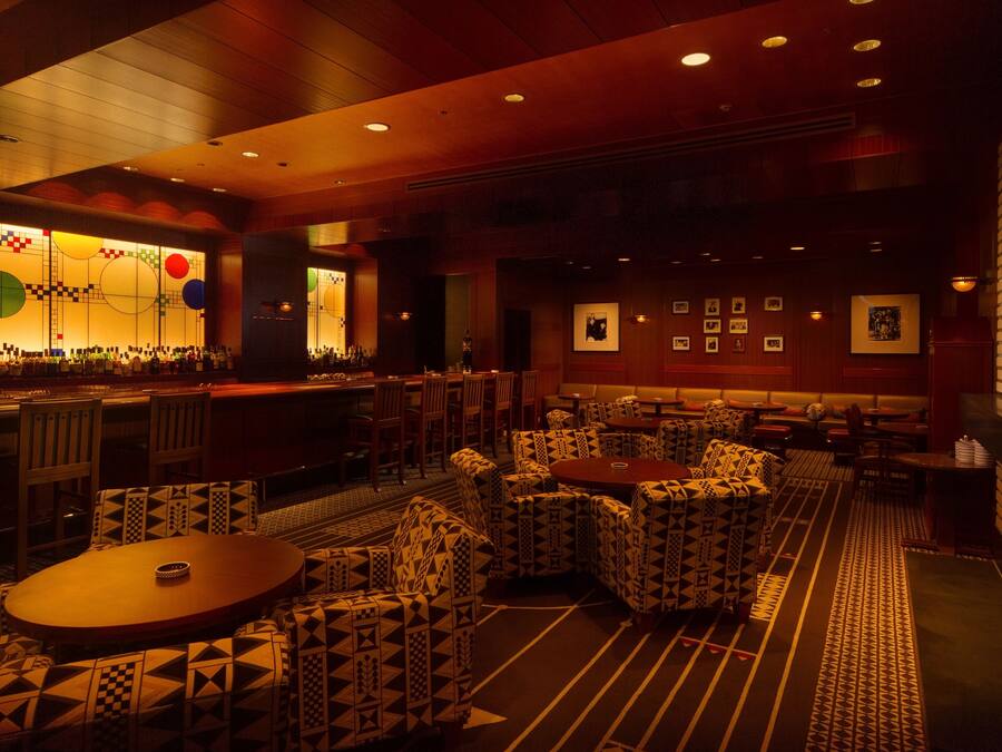 A restaurant with patterned seating, a bar area, and framed pictures on the walls.