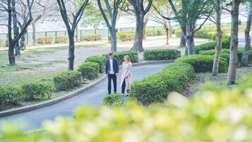 A couple walking on a curved pathway surrounded by trees and bushes.