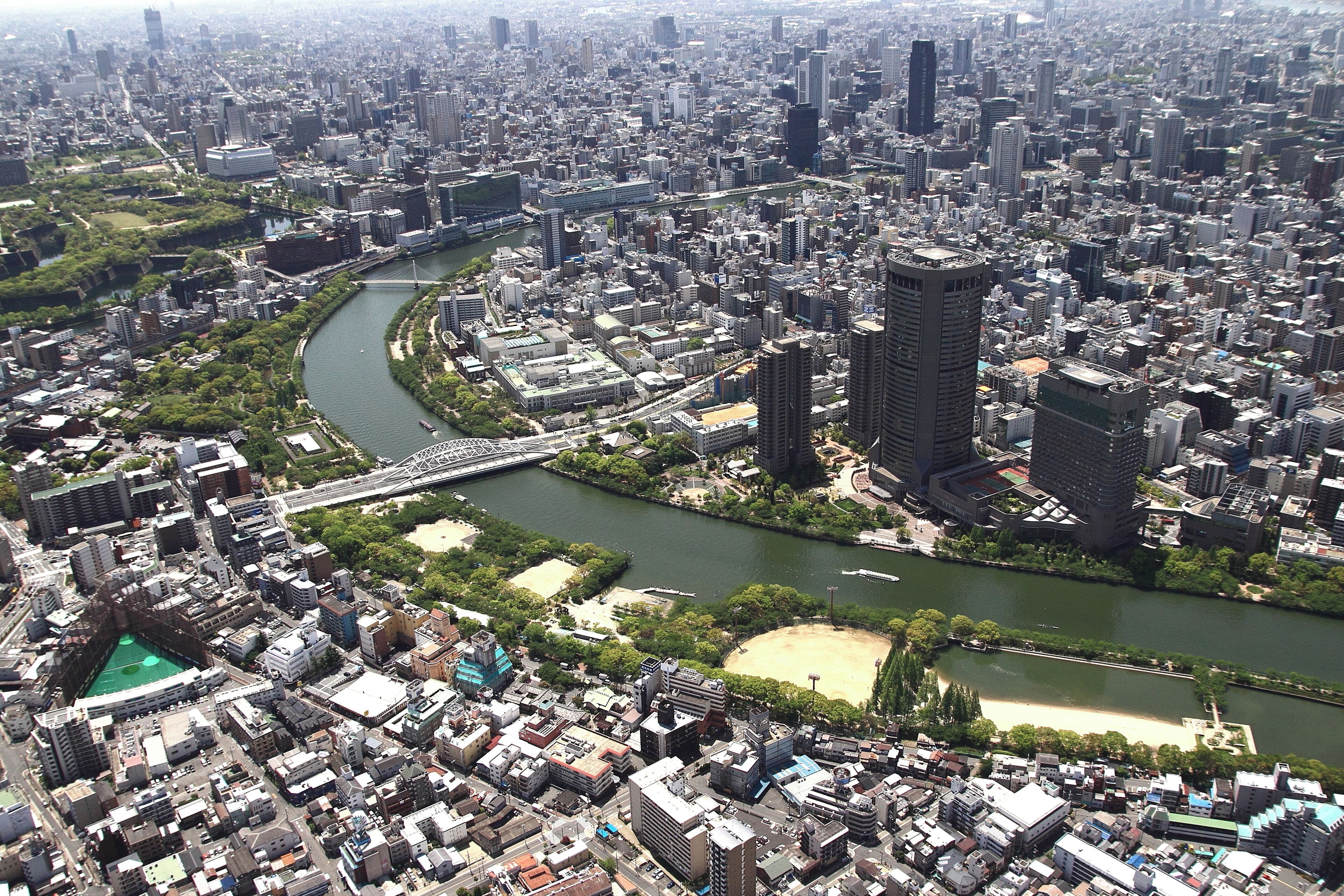 Uma área urbana densamente construída, com um rio, pontes e um estádio.