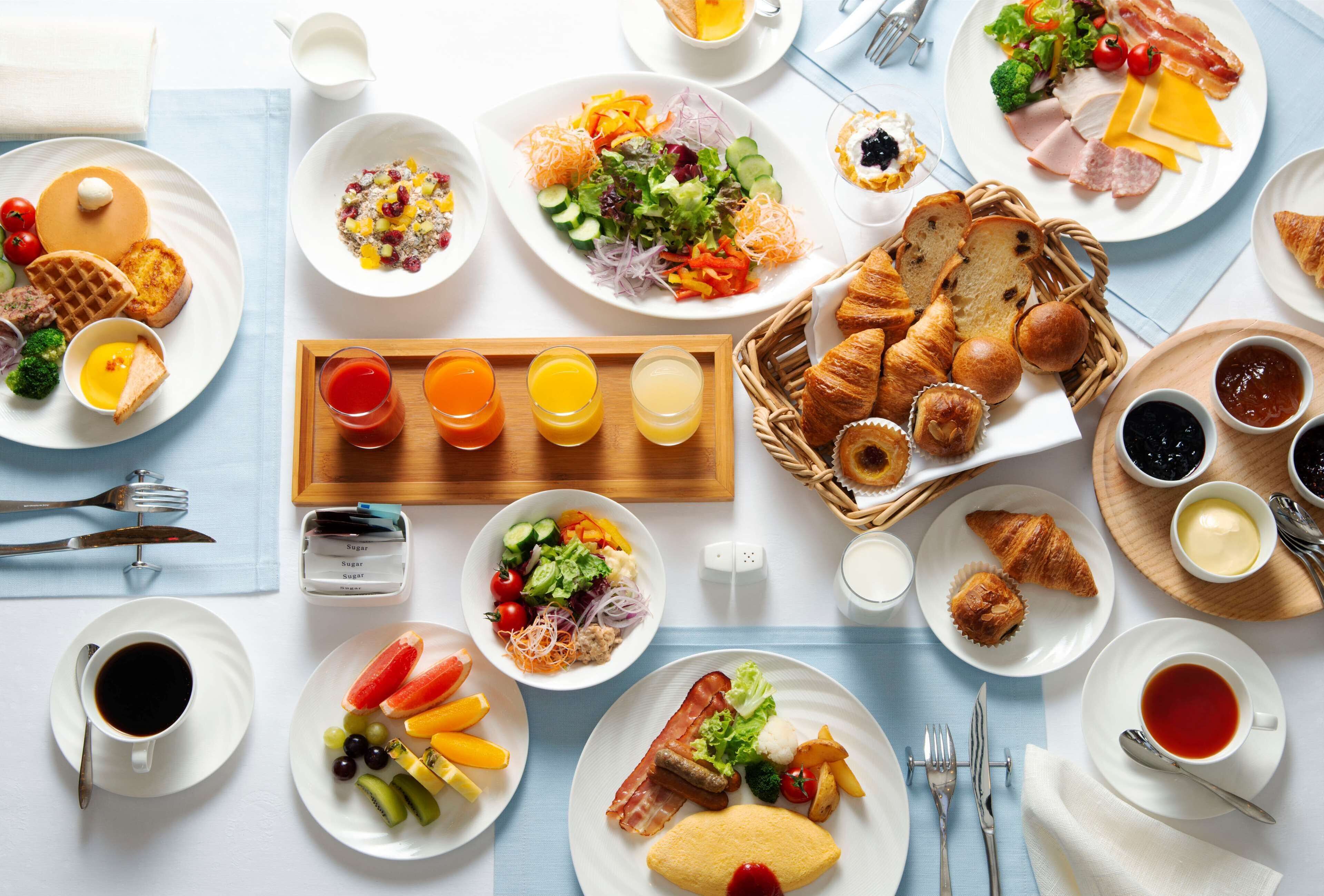 Un bufé de desayuno con diversos platos, bebidas y pan.