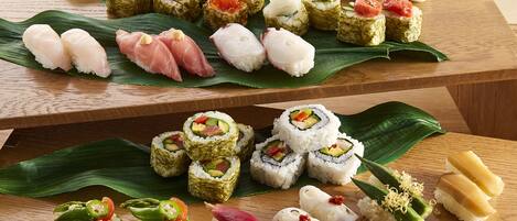 A variety of sushi on a wooden table with a green leaf.