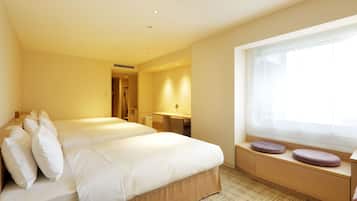 A hotel room with two beds, a desk, and a window with curtains.