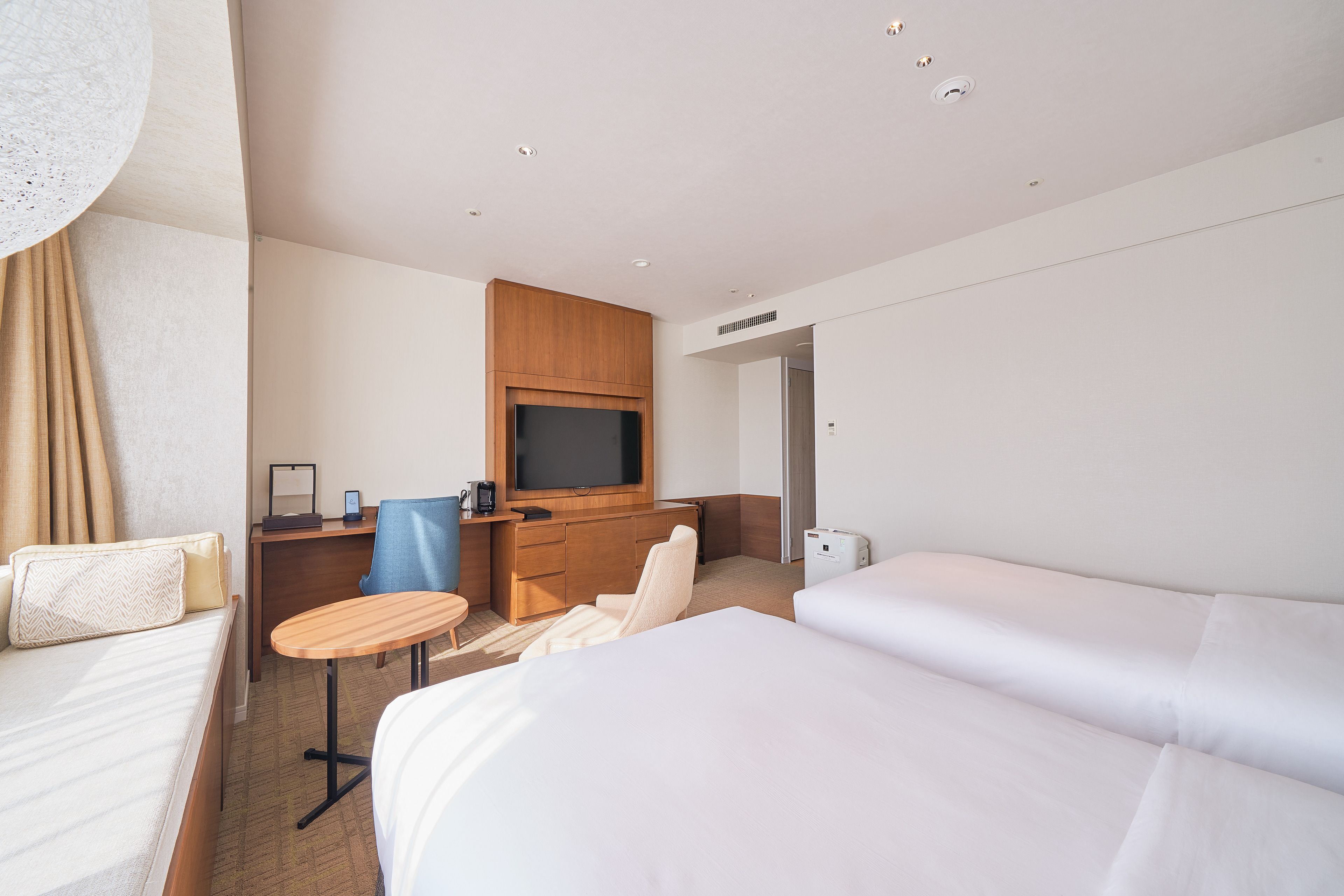 A hotel room with a bed, a desk, a chair, a television, and a small table.