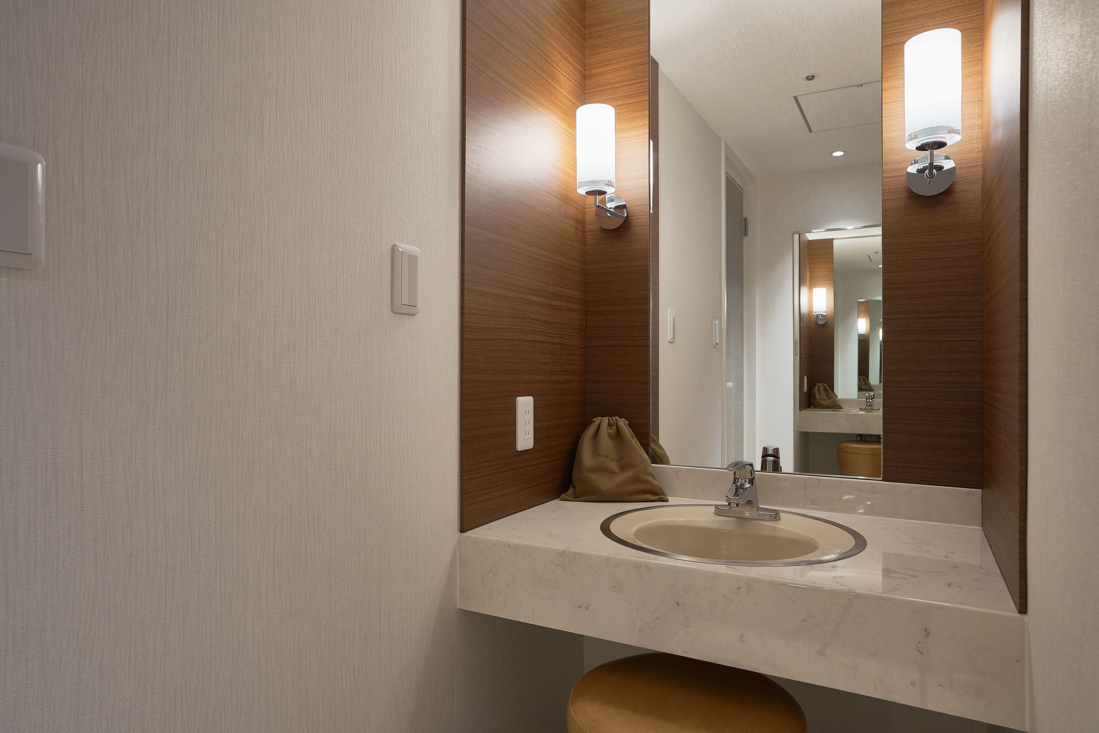 Une salle de bain moderne avec un lavabo en marbre, des murs recouverts de panneaux en bois et des appliques murales.