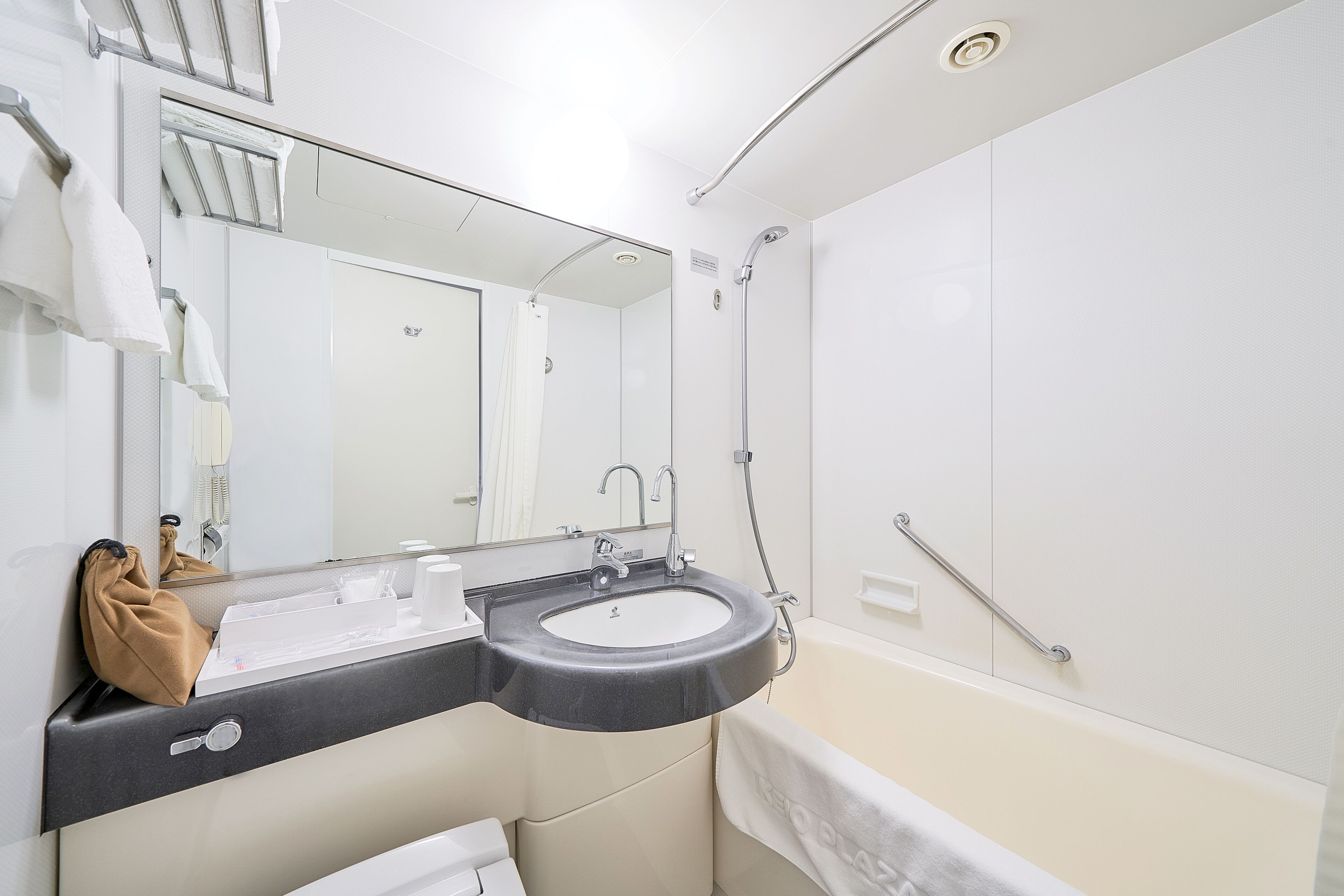 A modern bathroom with a black sink, white vanity, and a large mirror.
