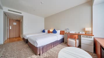 A hotel room with a large bed, a desk, a chair, and a small table.
