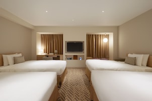 A hotel room with two beds, a TV, a desk, and a mirror.
