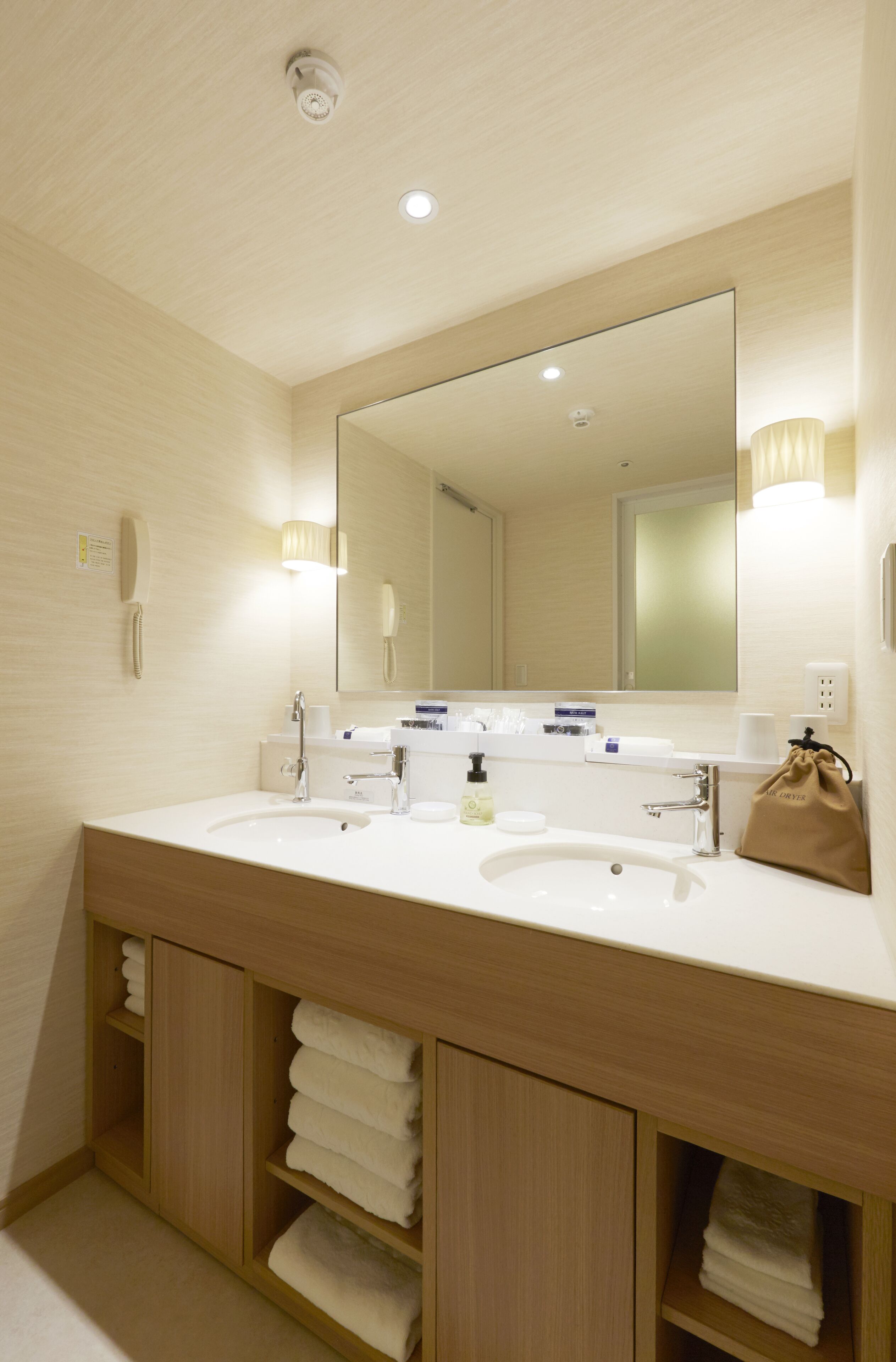 Uma casa de banho de hotel com duas pias, um espelho grande e espaço para toalhas.