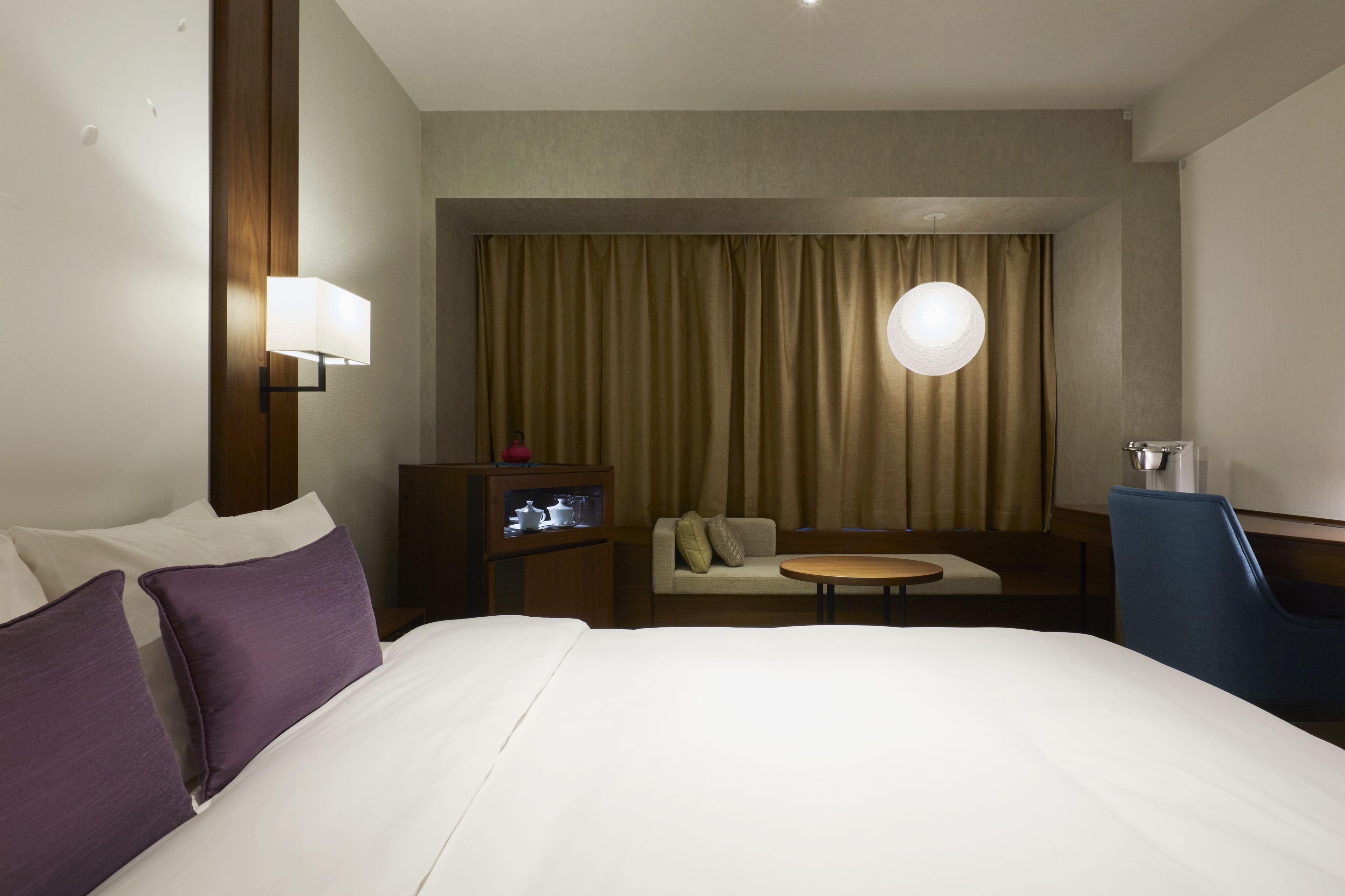 A hotel room with a large bed, a sofa, a small table, and a TV.