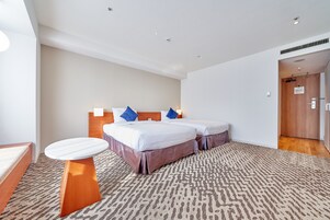 A hotel room with two beds, a small round table, and a patterned carpet.