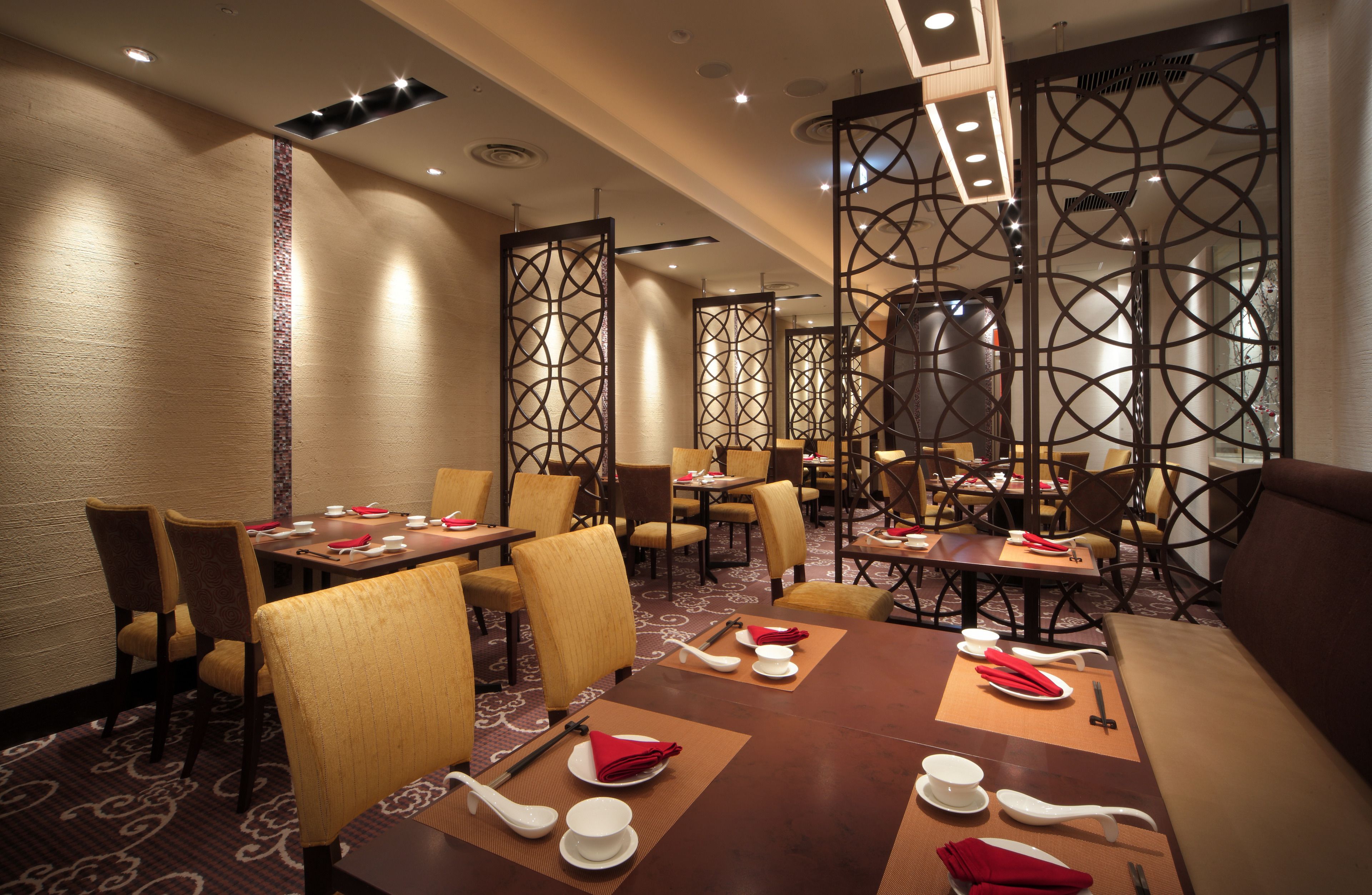 A dining area with tables set for a meal, chairs, and a decorative partition.