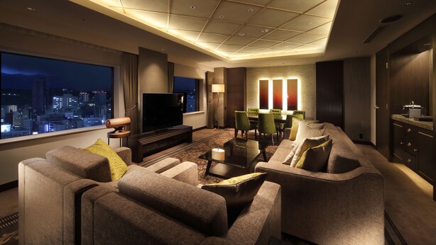 A modern hotel living room with a large TV, comfortable seating, a dining area, and a city view. - Hotel Metropolitan Sendai (Sendai)