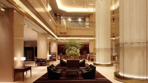 A spacious lobby with a central seating area, a large decorative column, and a staircase leading to an upper level. - Hotel Metropolitan Sendai (Sendai)