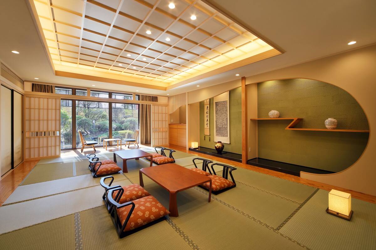 A traditional Japanese-style room with tatami flooring, low tables, and cushions.