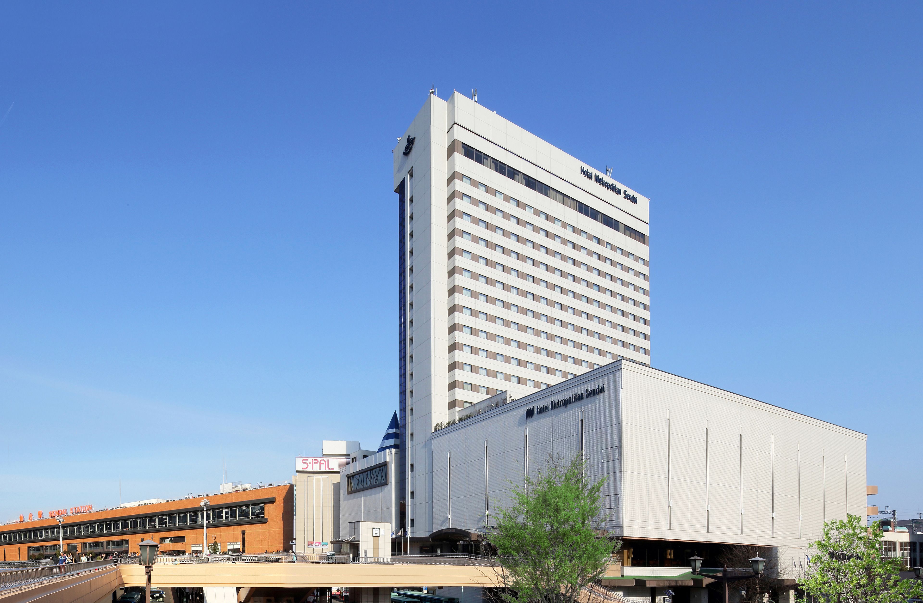 Un hotel alto de diseño moderno, con un letrero destacado y un edificio grande contiguo.