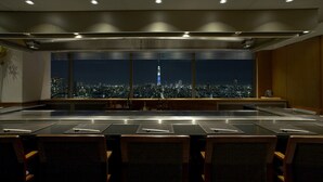 A conference room with a large table and chairs, a view of a cityscape at night, and a window with blinds. - Hotel East 21 Tokyo (Tokyo)
