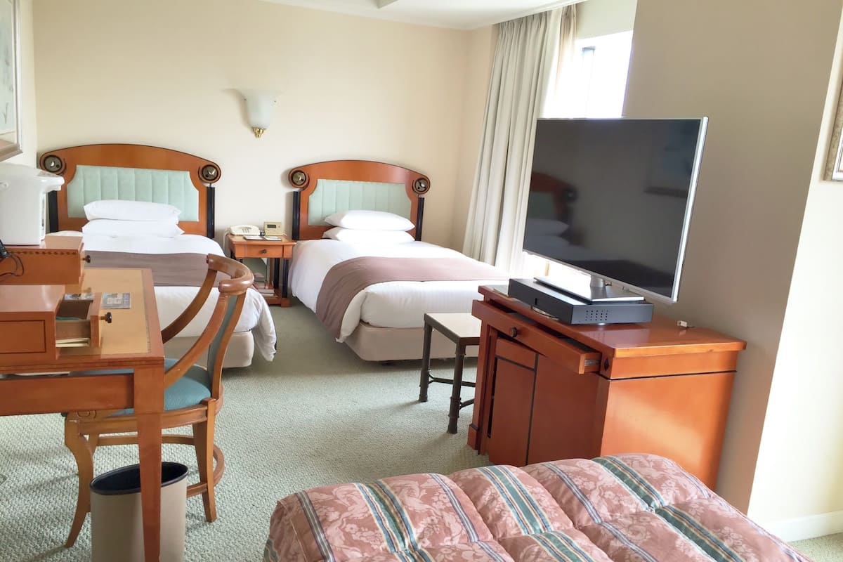 A hotel room with two beds, a TV, a desk, and a chair.