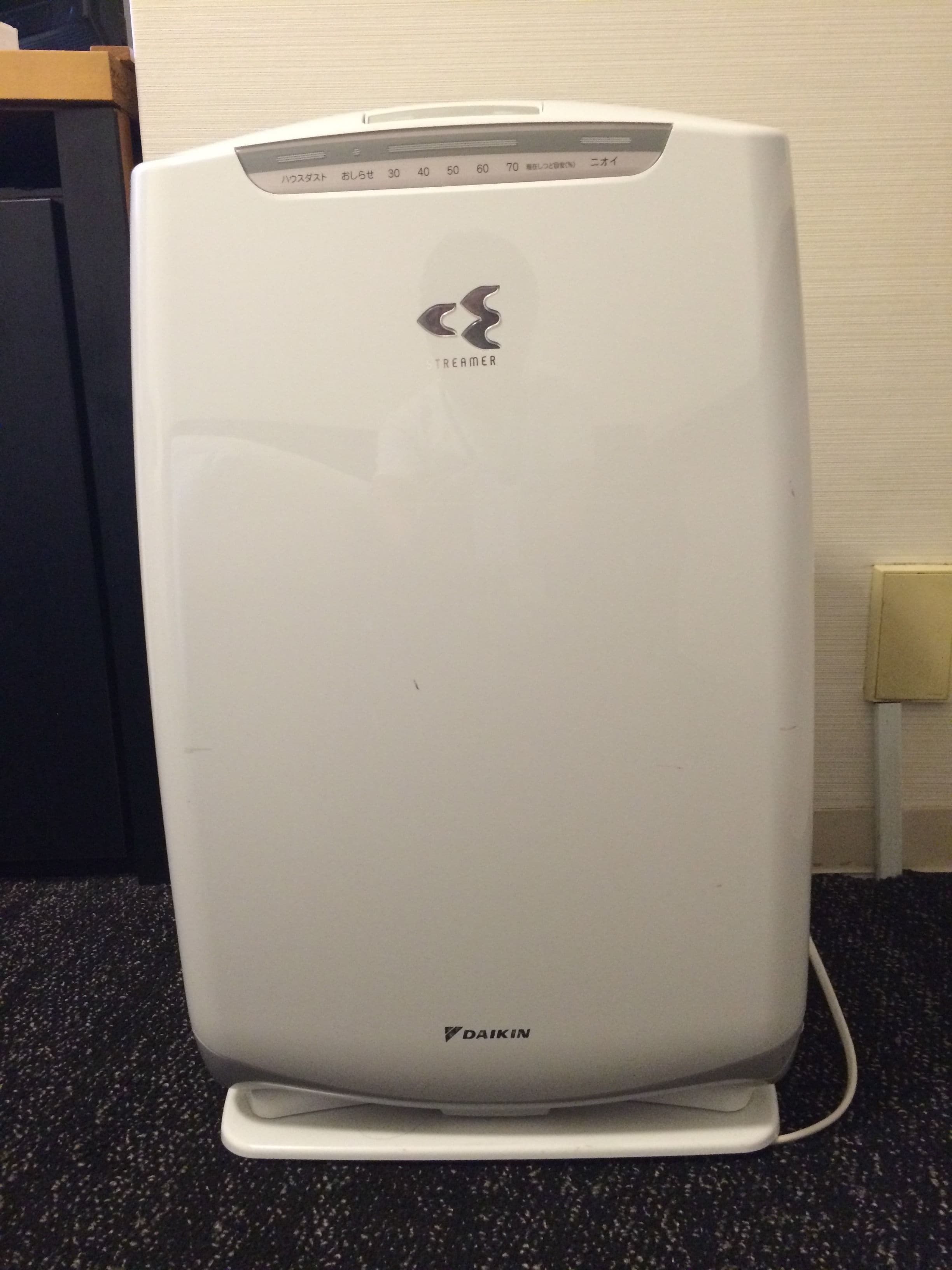 A white Daikin air conditioner unit with a control panel and brand logo.