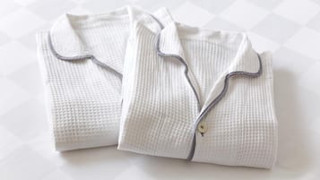 Two neatly folded white shirts with a textured pattern and dark trim.