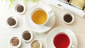 A table with two cups of tea, each with a different type of tea, and several small bowls containing various tea leaves.