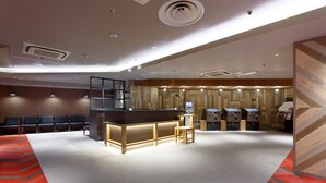 Een hotel lobby met een receptiebalie, een zithoek en bedieningsautomaten.