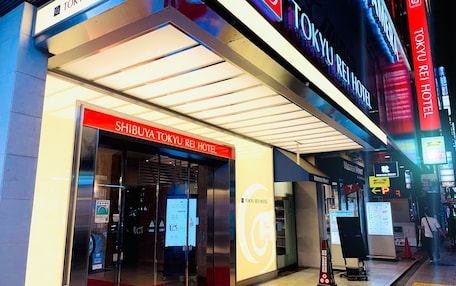 The exterior of the Shibuya Tokyo Rei Hotel with illuminated signage and a red carpet entrance.