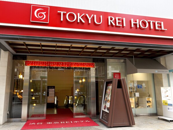 The entrance to the Tokyo Rei Hotel with a red awning and a glass door.