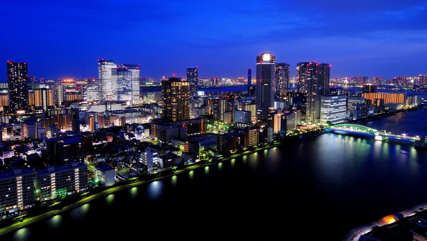 A nighttime cityscape with high-rise buildings along a river, illuminated by artificial lighting. - Ginza Creston (Tokyo)