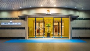 The entrance of the Ginza Creston Hotel with a blue mat in front, a signboard, and a reception area visible through the glass doors. - Ginza Creston (Tokyo)