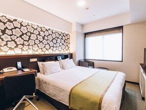 A hotel room with a large bed, a desk with a phone, a chair, a window with a view, and a decorative wall with a floral pattern. - Shinagawa Tobu Hotel (Tokyo)